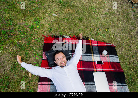 Image of businessman relaxing on the grass with laptop near by Stock Photo