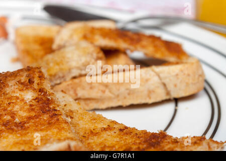 Close up shot of a golden brown buttered slice of toast on a white pattened plate Stock Photo