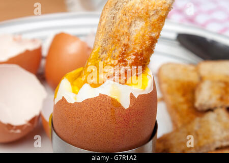 Close up shot of a golden toasted bread soldier dipped in a runny egg on a plate Stock Photo