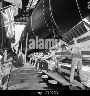 The setting up ceremony at HM Dockyard, Chatham, Kent, as shipwrights, working in unison, raise the submarine Okanagan on the launching way by hammering wedges under the launching cradle. She will be named by Madame Cadieux, wife of the Associate Minister of National Defence for Canada. Okanagan is the third and last of the present series of Oberon class submarines built for Canada. She will be ready for service in about a year. Stock Photo