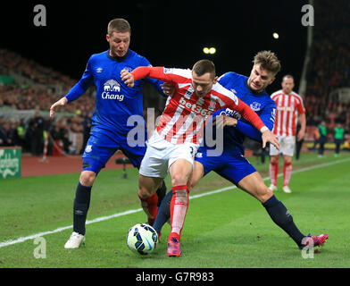 Everton's Luke Garbutt (right) and James McCarthy (left) battle for the ball with Stoke City's Phil Bardsley during the Barclays Premier League match at the Britannia Stadium, Stoke. Stock Photo