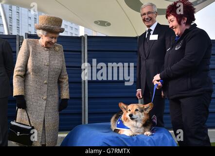 Queen Elizabeth II looks at a Corgi as Paul O'Grady looks on during a visit to Battersea Dogs and Cats Home in London. Stock Photo