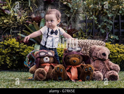 Baby boy playing with teddy bears at the garden, learning to walk Stock Photo
