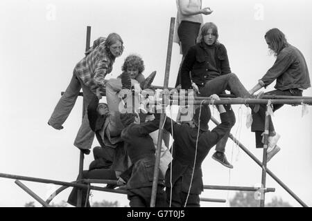 Free Pop Festival fans clamber up scaffolding poles in their bid to evade the arm of the law at Windsor Great Park after 600 police moved in to break up the event which got underway last weekend. Policemen's uniforms and fans clothes were torn in some scuffles. Stock Photo