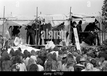 Hundreds of Policemen were at the scene of this week's pop festival at Windsor Great Park, some forming a cordon round the remaining supporters. One of the police officers is seen carrying his truncheon. Stock Photo