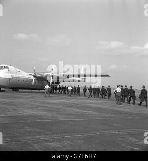 Beneath the wing of a Royal Air Force Transport Command Argosy, Britain's first flying police force, march out in step before leaving RAF Northolt, Middlesex, for Lydd, Kent. The policemen, 69 of them from the Metropolitan force, were en route for Hastings after sporadic outbreaks of trouble. Mods and Rockers had descended on the town. Stock Photo