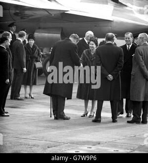 Smiling, Queen Elizabeth II and Prince Philip the Duke of Edinburgh say goodbye with handshakes at London Airport before boarding a BOAC Britannia liner to fly to New Delhi. Far right is the Prime Minister, Harold Macmillan. The Queen, wearing a light brown mink coat over a royal blue dress and a hat of royal blue and vivid green velvet petals, and the Duke were leaving for a 20,000 mile tour of India, Pakistan, Nepal and Iran. Stock Photo