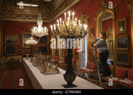 English Heritage historic property steward Jennifer Watling cleaning one of the lights in the Waterloo Gallery in Apsley House in London in preparation for the bicentenary the Battle of Waterloo. Stock Photo