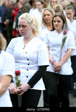 The hearse carrying the coffin of Karen Buckley is flanked by nurses from her University of Limerick graduation year at the Church of St. Michael the Archangel, Analeentha, Co. Cork. PRESS ASSOCIATION Photo. Picture date: Tuesday April 28, 2015. The emotional funeral of the murdered student has been told of the indescribable hurt and pain wreaked on her devastated family by an utterly inappropriate death. Amid heartbreaking scenes in her native Mourneabbey, near Mallow, Co Cork, the tragic student's brothers placed a poignant photograph of her as a child starting school, as well as her nurse Stock Photo