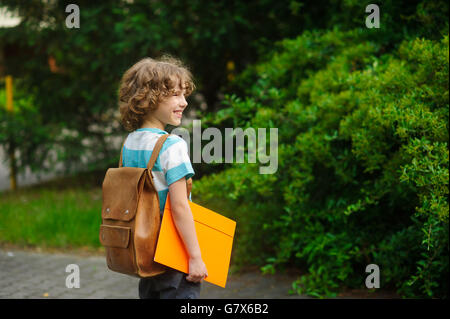 Chappy on a schoolyard. The school student stand in a half-turn to the camera. He looks in a distance and smiles. Against magnif Stock Photo