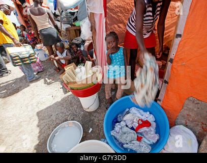 June 27, 2016 - Port-Au-Prince, Florida, U.S. - 061110 (Lannis Waters/The Palm Beach Post) PORT-AU-PRINCE, HAITI - A woman does laundry in front of her tent as vendors ply their goods in the background at the sprawling Golf Club refugee camp, on the grounds of the Petionville Club. An estimated 20,000 people are living in the camp; 25,000 before 5,000 were relocated to the Corail camp outside of Port-au-Prince. (Credit Image: © Lannis Waters/The Palm Beach Post via ZUMA Wire) Stock Photo