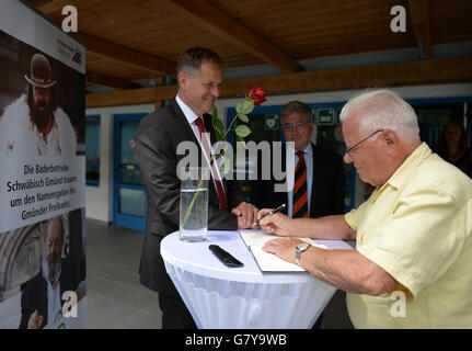 Schwaebisch Gmuend, Germany. 28th June, 2016. Contemporary witness Manfred Bihr writing in the book of condolence for Bud Spencer, while Richard Arnold (l), Mayor of Schwaebisch Gmuend, and Rainer Steffens, CEO of the public services, stand in the back at the Bud Spencer public pool in Schwaebisch Gmuend, Germany, 28 June 2016. Manfred Bihr had met Bud Spencer three times and once shook his hand, even though he could not understand him. Bihr describes the Italian actor and former athlete as a sports comrade and casual guy. PHOTO: JAN-PHILIPP STROBEL/dpa/Alamy Live News Stock Photo
