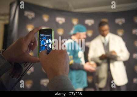 American Football - Jackson Jaguars NFL Draft - Trickbox Studio. A picture is taken on a mobile phone as Former Jaguars player Marcus Stroud (right) signs autographs for fans during the NFL draft Stock Photo