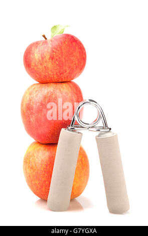 carpal expander and a stack of three red apples with green leaf on white background.  fitness concept. Stock Photo
