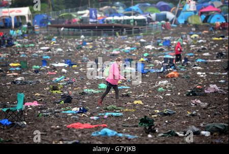 Festivalgoers walk through the aftermatch of Glastonbury Festival, at Worthy Farm in Somerset. Stock Photo