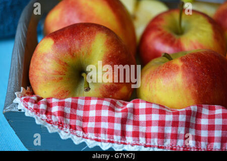 close up of red, yellow ,green apples in a wooden bowl with red white nostalgic  countryside checkered doily Stock Photo