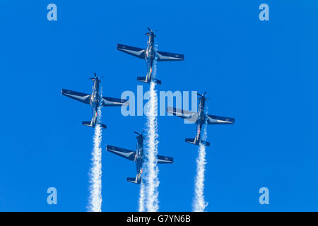 Acrobatic military turbo prop planes flying formation in blue sky. Stock Photo