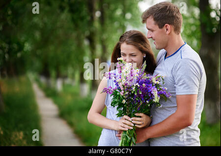 beautiful couple in love walking with a bouquet of wildflowers Stock Photo