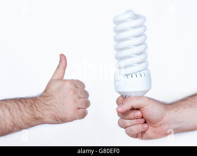 Concept of energy saving, a hand holding a fluorescent lightbulb while another hand showing ok sign, thumbs up Stock Photo