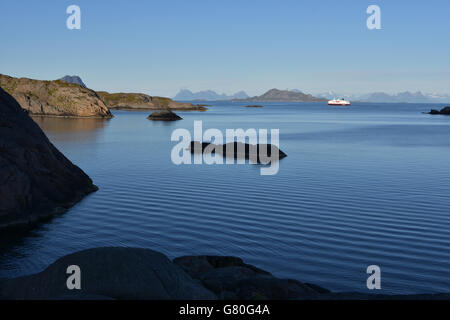 Nordlys Hurtigruten coastal ferry northbound, Lofoten, with snowy mountains, blue Stock Photo