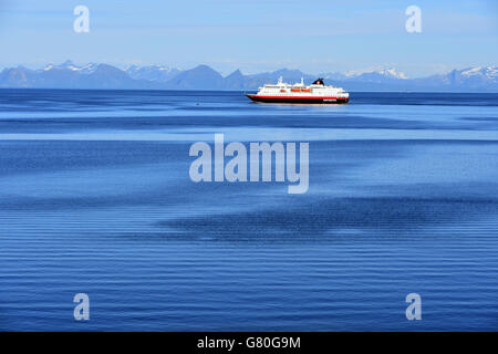 Nordlys Hurtigruten coastal ferry northbound, Lofoten, with snowy mountains, blue Stock Photo