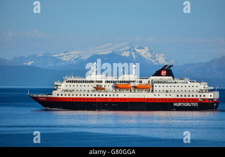 Nordlys Hurtigruten coastal ferry northbound, Lofoten, with snowy mountains, blue Stock Photo