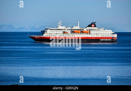 Nordlys Hurtigruten coastal ferry northbound, Lofoten, with snowy mountains, blue Stock Photo