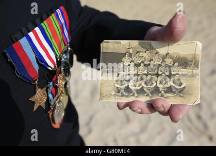 Normandy veteran Alan King, from the Norwich and District NVA, holds a photo of himself (front second left) and his comrades from B Company taken on VE Day 1945, whilst visiting Sword Beach, Normandy, France, as dozens of British veterans made a cross-Channel pilgrimage to Normandy to honour the legacy of comrades killed in the D-Day landings 71 years ago. Stock Photo