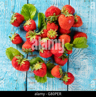 Fresh strawberry pile with leaves placed on old wooden planks. Shot from aerial view Stock Photo