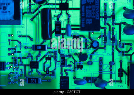 Technology concept . Circuit board / pcb showing components lit with blue and green light. Wiring inside computer, circuit close up, electronics. Stock Photo