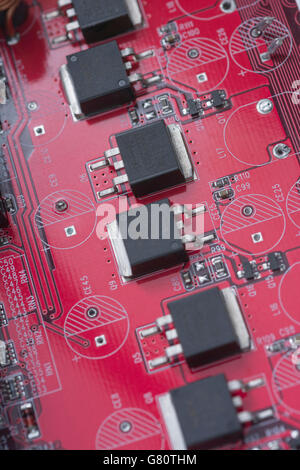 Technology concept. Red circuit board / red pcb showing series of semiconductor components. Wiring inside computer, circuit  close up, electronics Stock Photo