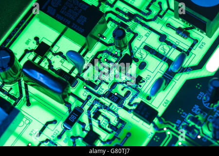 Technology concept . Circuit board / pcb showing components lit with blue and green light. Wiring inside computer, circuit close up, electronics.