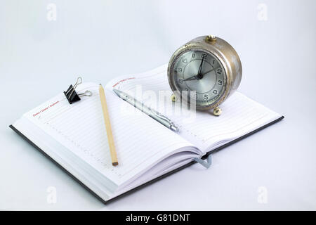 Empty organizer with a pen and paperclips next to a vintage oldfashioned clock Stock Photo