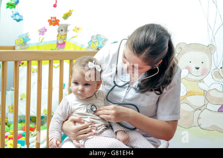 Young nurse taking care of baby girl in her own badroom