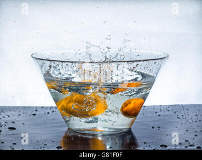 Orange splashes water in a big bowl on a black table Stock Photo
