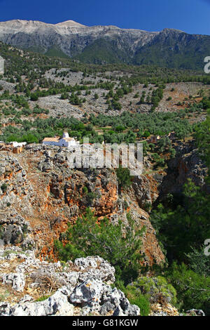 A whitewashed, red tiled roof church perches on a craggy cliff overlooking the Aradena Gorge in a remote  part of southern Crete Stock Photo