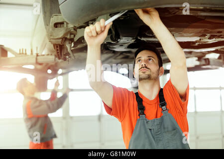 Car mechanic upkeeping car in dealership garage