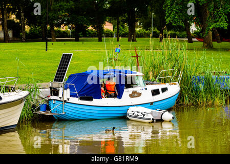 Soderkoping, Sweden - June 20, 2016: Small motorboat with solar panel in the aft. Adult woman and child seen under the blue tarp Stock Photo