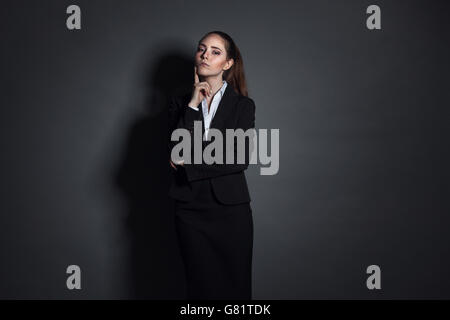 Portrait of young businesswoman in black suit on dark background Stock Photo