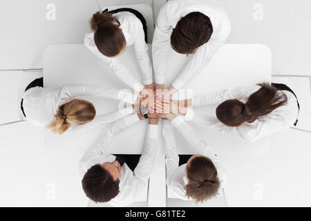 Businesspeople sitting around the table stacking hands one over each other Stock Photo