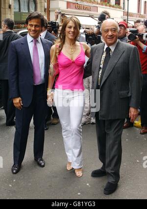 Model and actress Elizabeth Hurley is flanked by her husband Arun Nayar (left) and Harrods boss Mohammed Al Fayed as she arrives to launch her new beachwear collection 'Elizabeth Hurley Beach'. Stock Photo