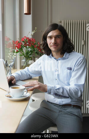Portrait of man using laptop while having coffee at cafe Stock Photo