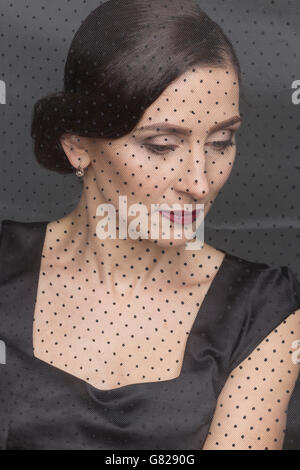 Beautiful woman in black dress seen through net Stock Photo