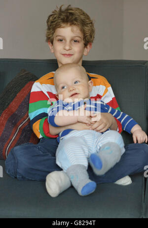 Boy sitting with toddler on sofa at home Stock Photo