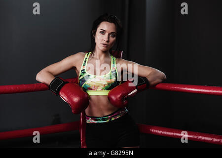 Portrait of female boxer leaning at corner in boxing ring Stock Photo