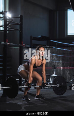 Young woman lifting barbell in gym Stock Photo