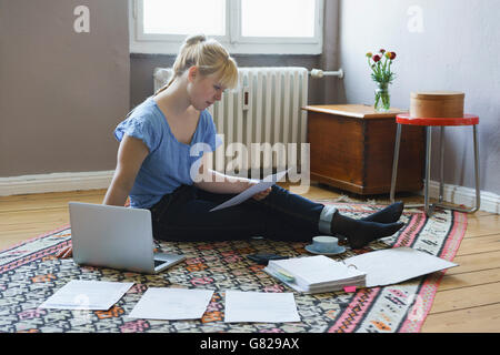 Woman using laptop while doing paperwork at home Stock Photo