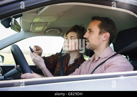 Couple using mobile phone for checking direction while sitting in car Stock Photo