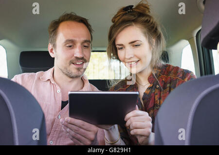 Happy couple using digital tablet while traveling in car Stock Photo