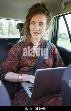 Thoughtful young woman using laptop in car Stock Photo